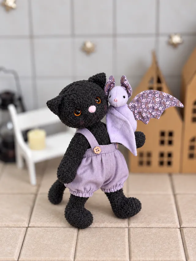 Чёрный котик в сиреневых штанишках с маленькой летучей мышкой на плече